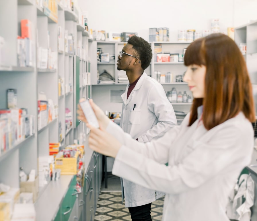 A male and a female pharmacists are looking at medications at a pharmacy