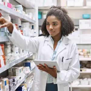 A young pharmacy resident sorts medications while holding a notepad.